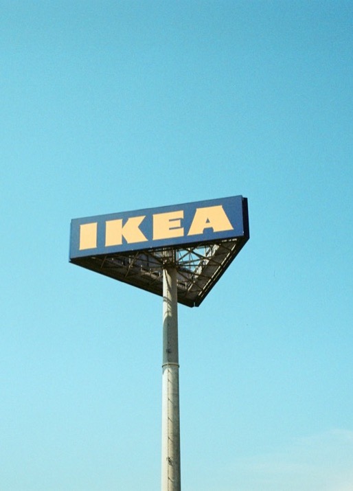 A tall Ikea sign on a tower, with a sky blue background. 