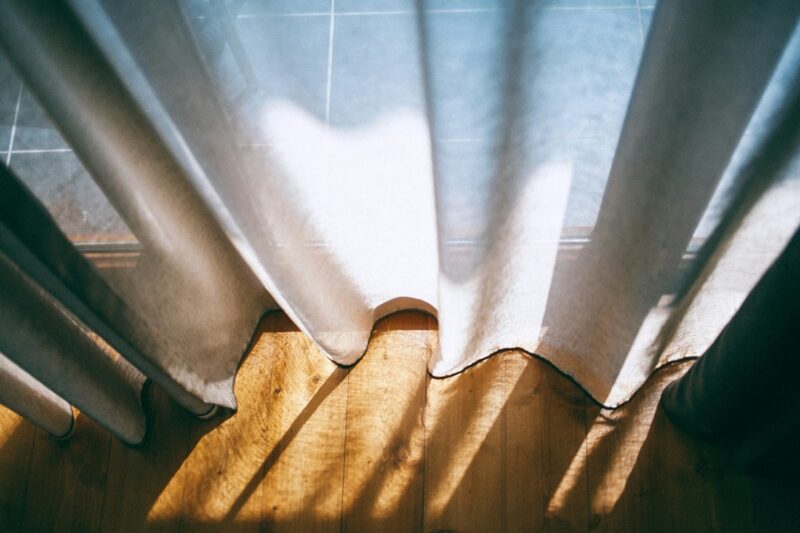 Curtains draped across the floor with soft sunlight streaming through. 